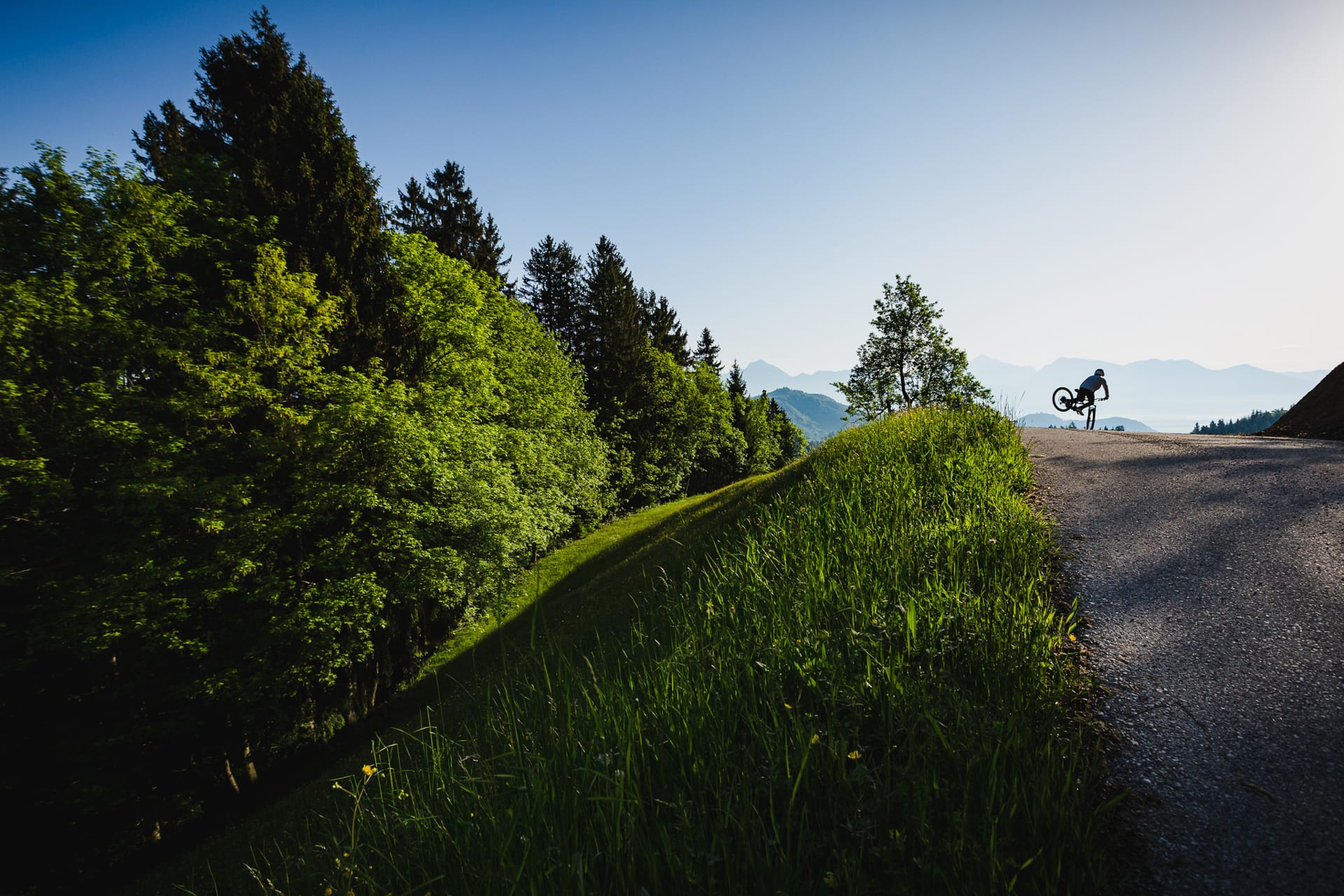 BineZalohar@KeepBusybyLegitFilms©KatjaPokorn Mountain biker on beautiful countryside road performing front wheelie