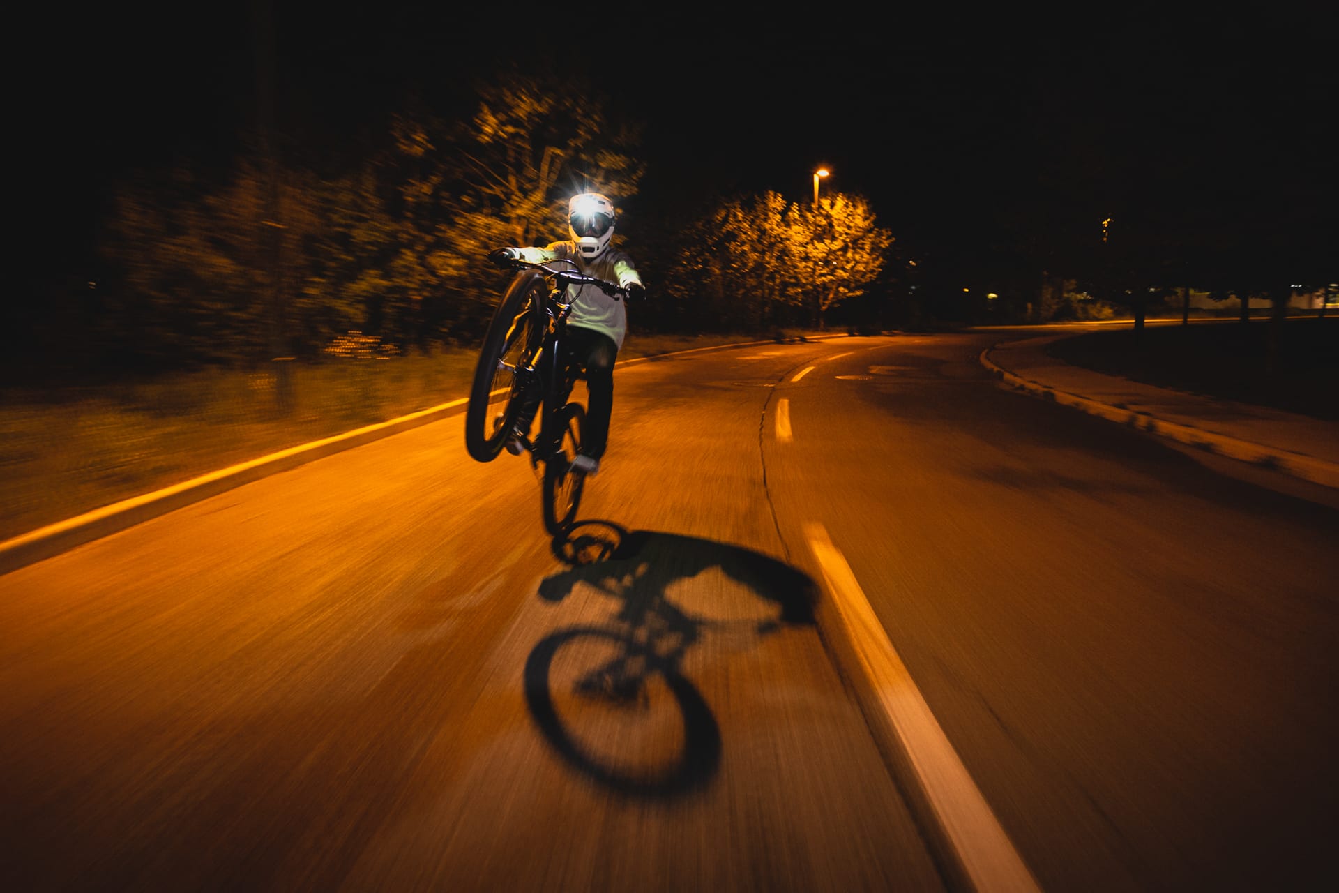 BineZalohar@KeepBusybyLegitFilms©KatjaPokorn Motion blur with a biker riding wheelie on an asphalt road in the night